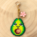 Porte-clé et bijou de sac soré Pixel art en perles thermocollés Avoki l'avocat avec sa fleur de cerisier.