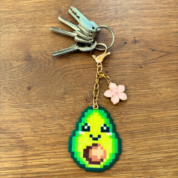 Porte-clé et bijou de sac soré Pixel art en perles thermocollés Avoki l'avocat avec sa fleur de cerisier utilisé en porte-clé avec des clés.