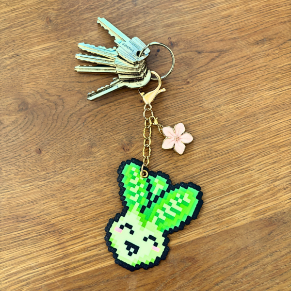 Porte-clé doré en Pixel art Pakou le pak choi en perles thermocollantes avec sa fleur de cerisier rose utilisé en porte-clé et accroché à des clés.